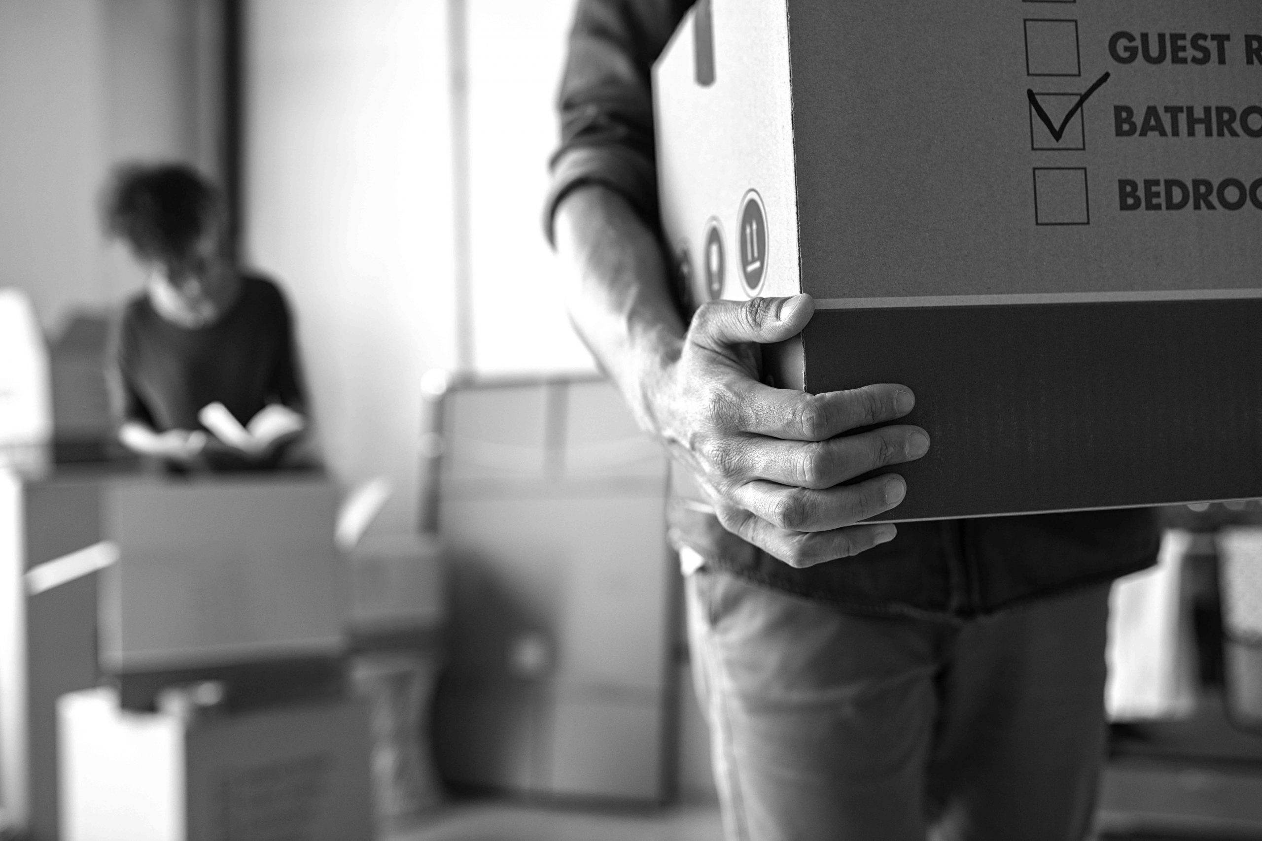 Closeup of man hand holding cardboard at new home. Young man unpacking boxes in new apartment. Man hand carrying carton box while relocating with his girlfriend.